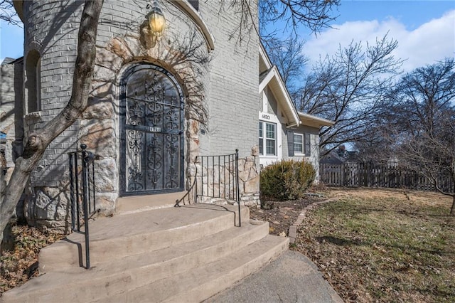 property entrance featuring fence and brick siding