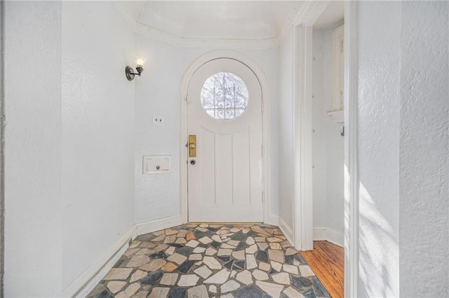 entryway with crown molding and baseboards