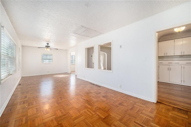 unfurnished room with a textured ceiling, a ceiling fan, and baseboards