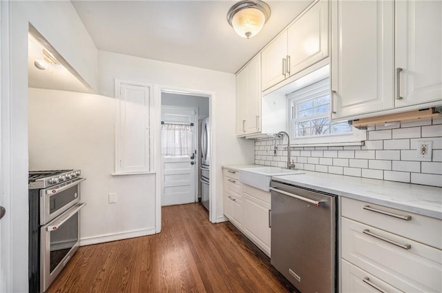 kitchen featuring tasteful backsplash, dark wood finished floors, white cabinets, appliances with stainless steel finishes, and a sink