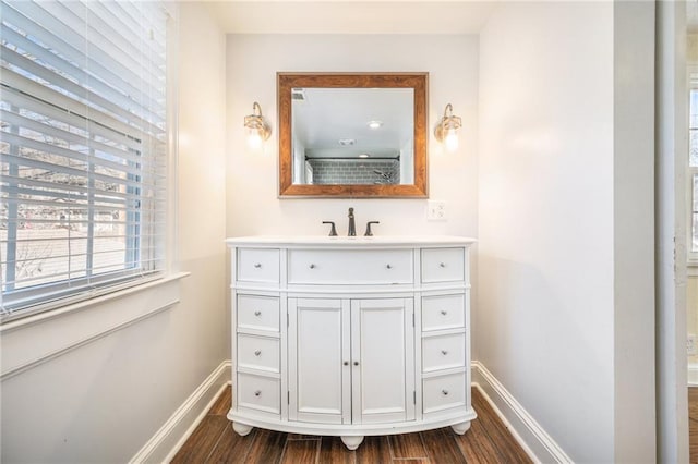 bathroom with baseboards, wood finished floors, and vanity