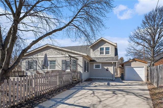 view of front of property with a fenced front yard, roof with shingles, concrete driveway, and an outbuilding