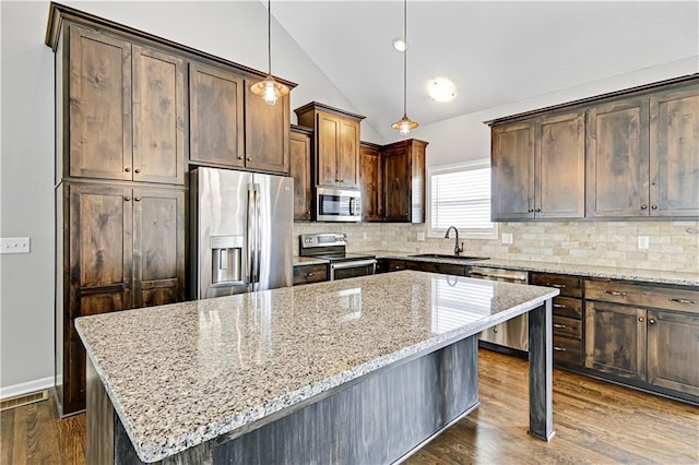 kitchen featuring appliances with stainless steel finishes, lofted ceiling, dark wood-style flooring, and a sink