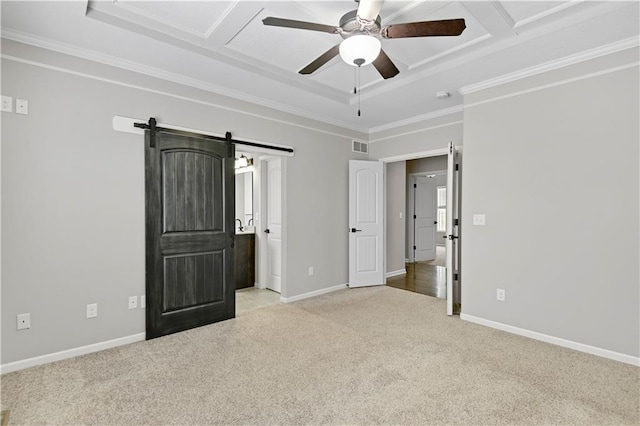 unfurnished bedroom with carpet floors, crown molding, baseboards, and a barn door