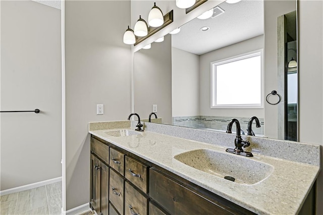 full bath featuring a sink, baseboards, and double vanity