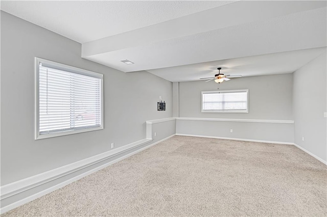 spare room featuring carpet, visible vents, baseboards, and ceiling fan