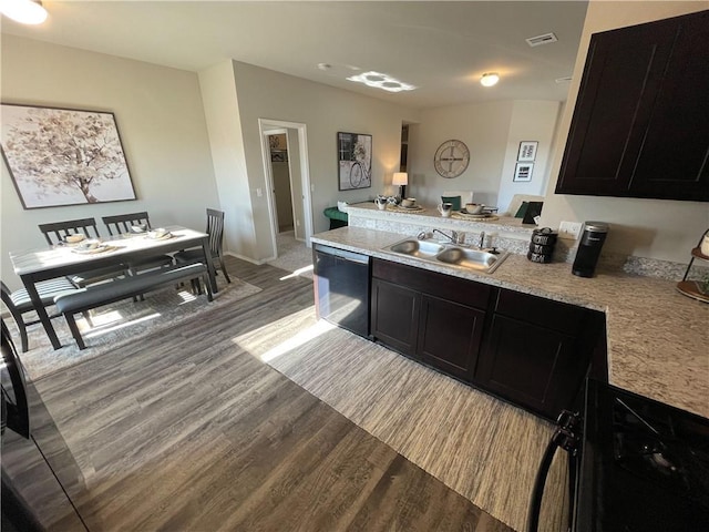 kitchen featuring a peninsula, a sink, dishwasher, and wood finished floors