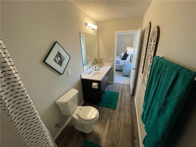 ensuite bathroom with visible vents, toilet, vanity, ensuite bath, and wood finished floors