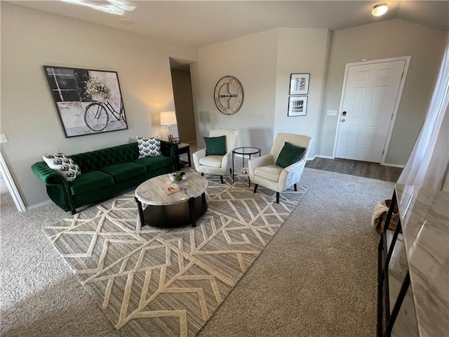 carpeted living area with vaulted ceiling and baseboards