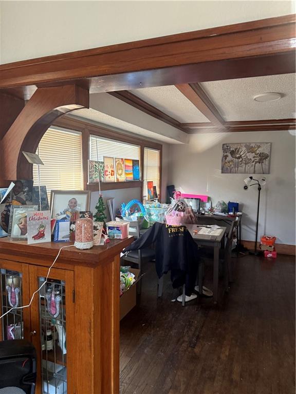 interior space with beam ceiling, a textured ceiling, and hardwood / wood-style floors