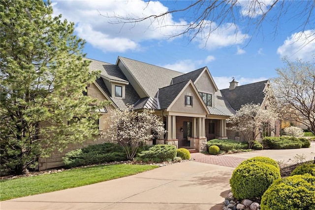 craftsman inspired home featuring a standing seam roof, covered porch, roof with shingles, and stone siding