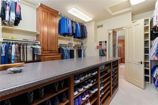 spacious closet featuring visible vents, attic access, and light colored carpet