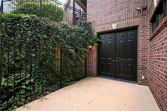 doorway to property featuring fence and brick siding