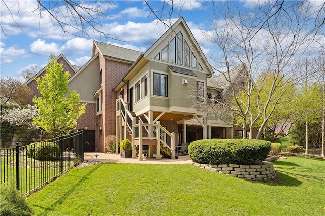 back of property featuring a lawn, a patio area, stairway, fence, and stucco siding