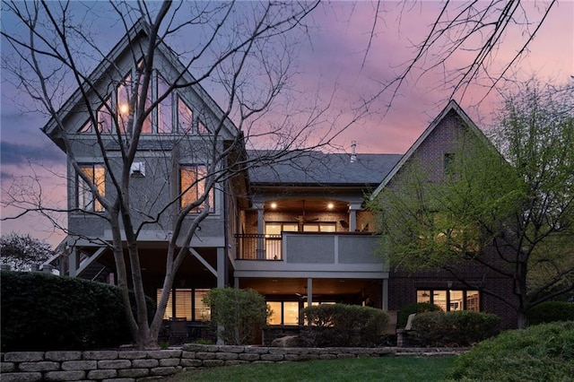 rear view of house featuring brick siding and a balcony