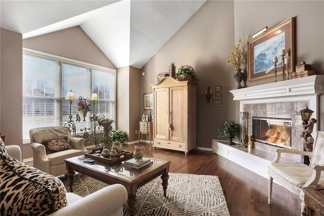 living area featuring high vaulted ceiling, baseboards, dark wood-type flooring, and a tiled fireplace