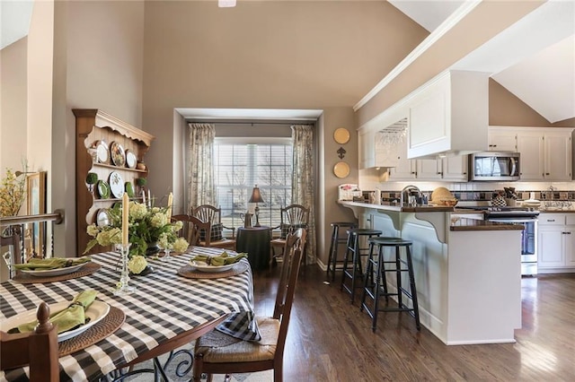 dining area with dark wood finished floors, ornamental molding, and high vaulted ceiling