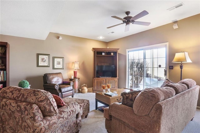 living room featuring visible vents, carpet floors, and a ceiling fan