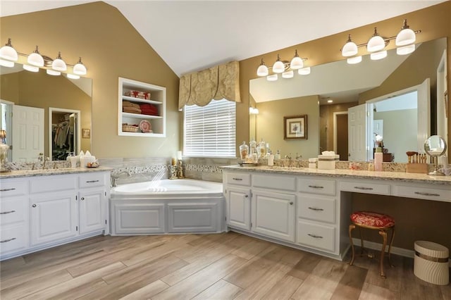 full bathroom featuring a garden tub, vanity, lofted ceiling, and wood finished floors