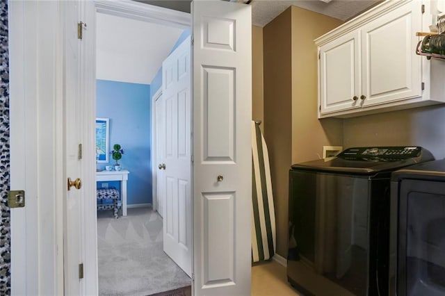 laundry area featuring baseboards, cabinet space, light carpet, and washer and clothes dryer