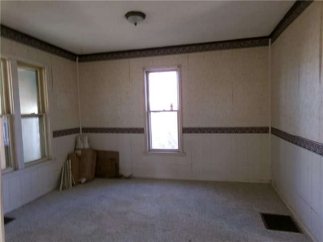 carpeted spare room with wainscoting, visible vents, and wallpapered walls