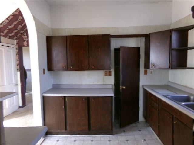 kitchen featuring light countertops, a sink, dark brown cabinetry, and light floors