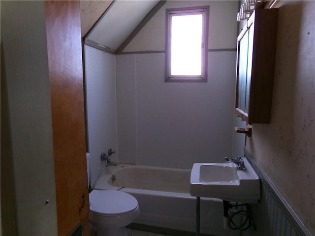 full bathroom featuring toilet, bathtub / shower combination, a sink, and wainscoting