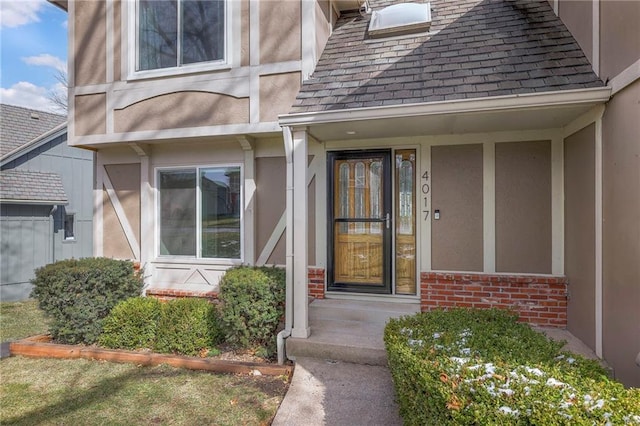 property entrance featuring brick siding, roof with shingles, and stucco siding