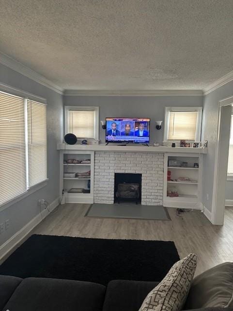 living area with wood finished floors, baseboards, a textured ceiling, crown molding, and a brick fireplace