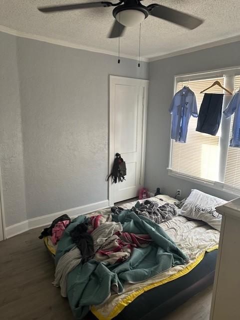 bedroom with baseboards, ceiling fan, ornamental molding, wood finished floors, and a textured ceiling