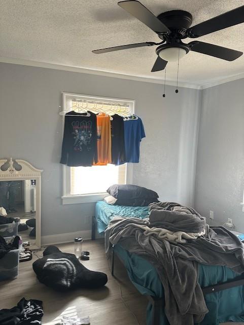 bedroom with a textured ceiling, wood finished floors, and ornamental molding