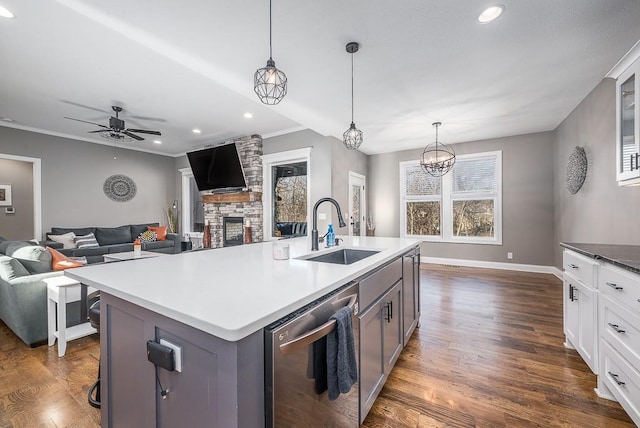 kitchen with a fireplace, a sink, dark wood-type flooring, dishwasher, and ceiling fan with notable chandelier