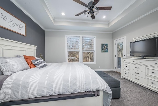 bedroom with a ceiling fan, baseboards, crown molding, a raised ceiling, and dark colored carpet