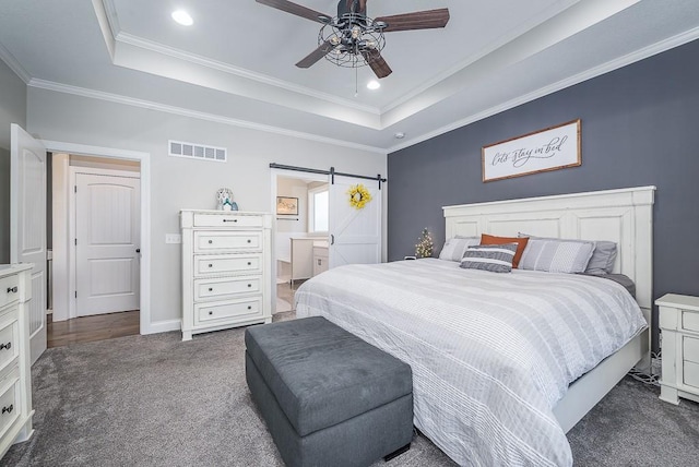 carpeted bedroom featuring visible vents, a raised ceiling, a barn door, and crown molding