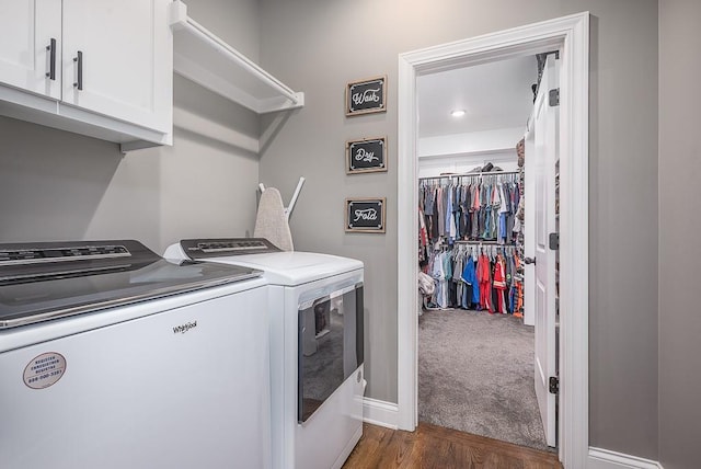 laundry room with baseboards, dark wood finished floors, washer and dryer, cabinet space, and dark colored carpet