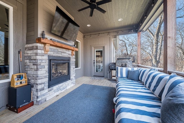 exterior space featuring wood ceiling, an outdoor stone fireplace, ceiling fan, and a wood stove