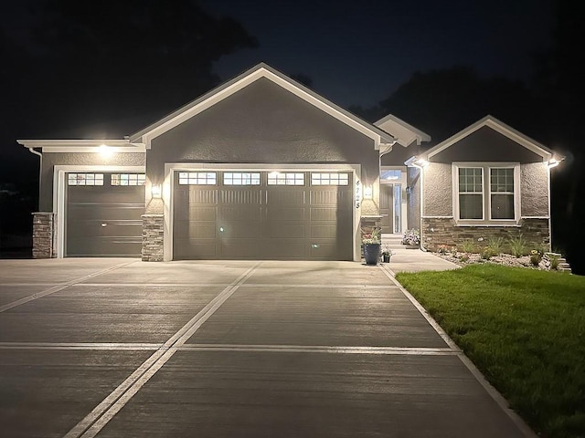 view of front of home featuring an attached garage, stone siding, driveway, and stucco siding