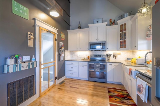 kitchen featuring visible vents, white cabinets, light wood-style floors, appliances with stainless steel finishes, and backsplash