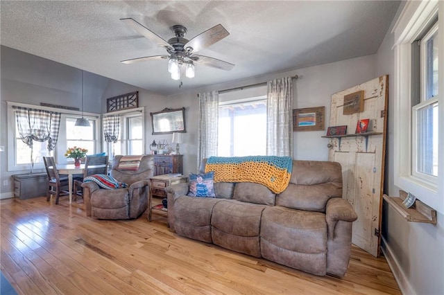 living room featuring a wealth of natural light, light wood-style flooring, a textured ceiling, and a ceiling fan