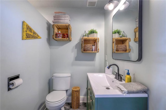 half bath with vanity, toilet, baseboards, and visible vents