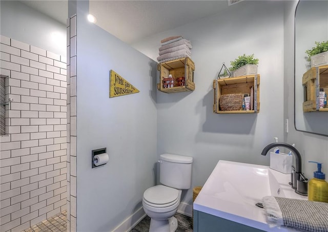 bathroom featuring baseboards, tiled shower, toilet, and vanity