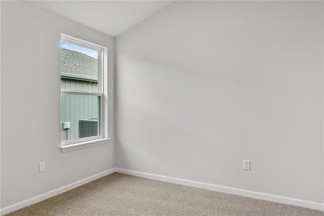 spare room with baseboards, vaulted ceiling, and carpet flooring