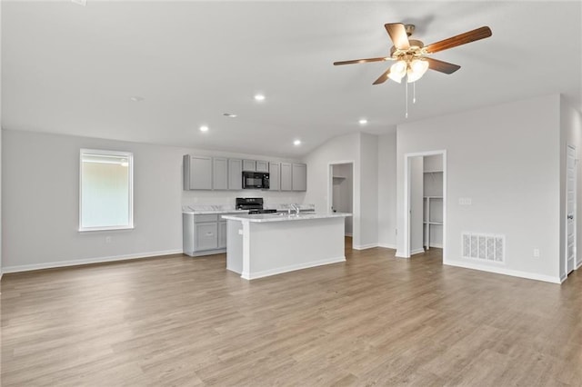 kitchen with black microwave, stove, visible vents, open floor plan, and gray cabinets