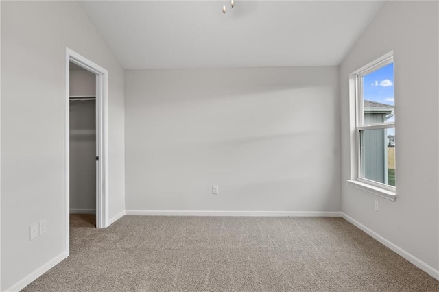 unfurnished bedroom with lofted ceiling, a closet, carpet flooring, and baseboards