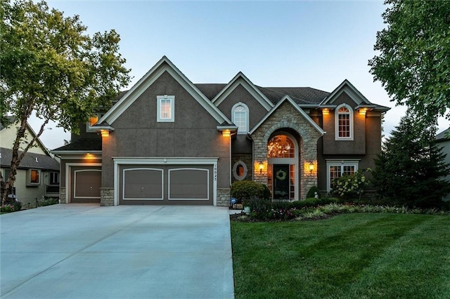 view of front facade featuring a front yard, stone siding, driveway, and stucco siding