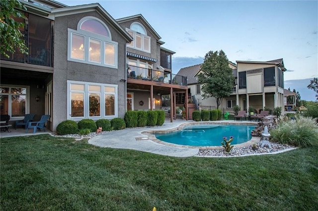 rear view of property with a yard, a patio, stucco siding, an outdoor pool, and stairs