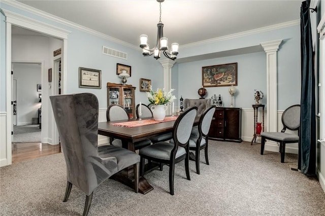 dining space with crown molding, a notable chandelier, light colored carpet, visible vents, and ornate columns