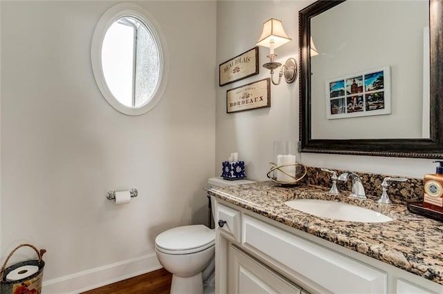 half bath featuring toilet, baseboards, wood finished floors, and vanity