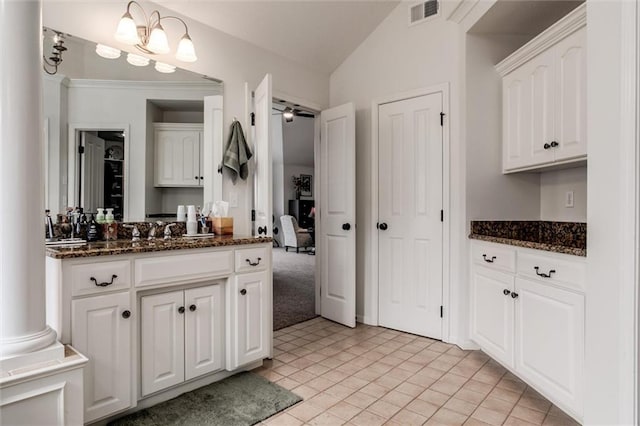 kitchen with vaulted ceiling, dark stone counters, visible vents, and white cabinets