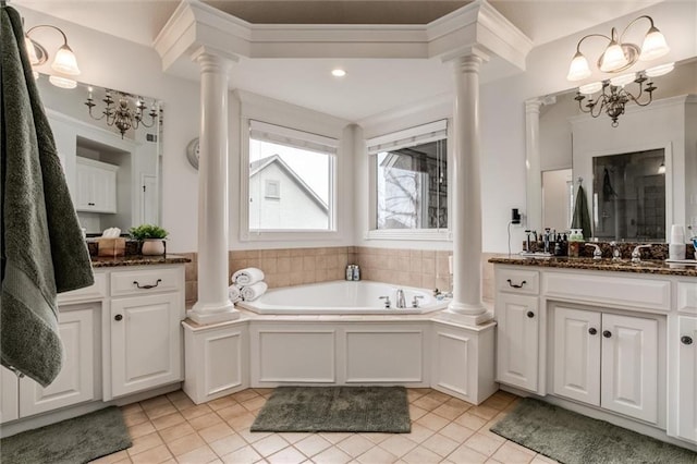 bathroom with ornate columns, tile patterned flooring, a bath, and vanity